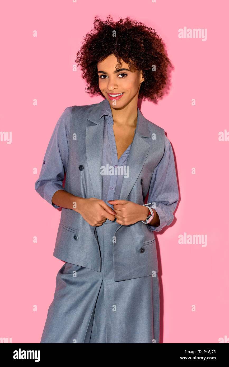 Young african amercian smiling girl in grey suit on pink background Stock Photo