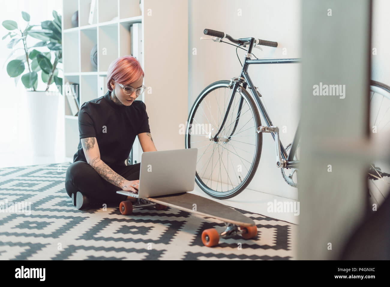 young businesswoman in eyeglasses using laptop on skateboard Stock Photo