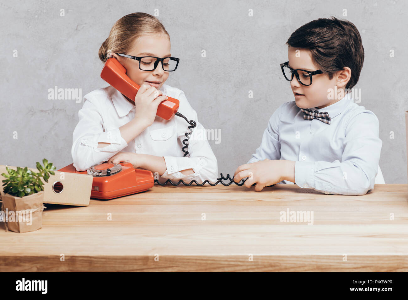 portrait of little girl talking on telephone while boy sitting near by at workplace Stock Photo