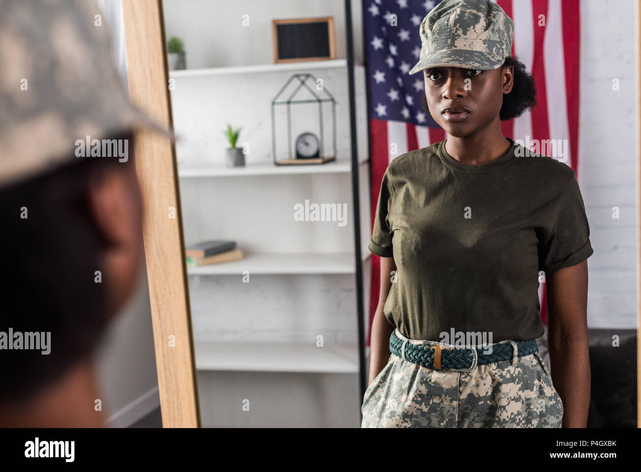 Female army soldier in camouflage clothes posing by the mirror Stock Photo