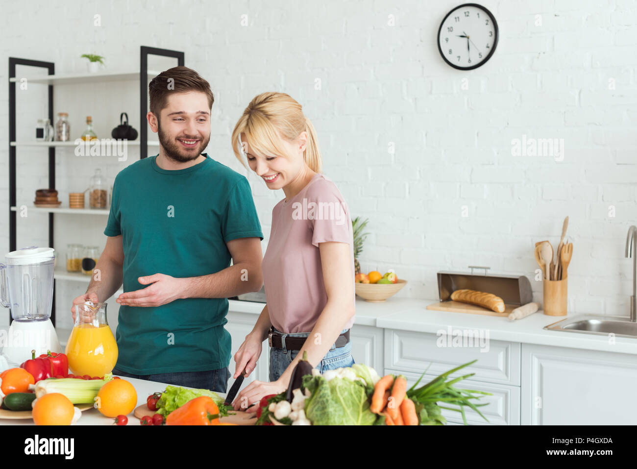smiling couple of vegans preparing food at kitchen Stock Photo