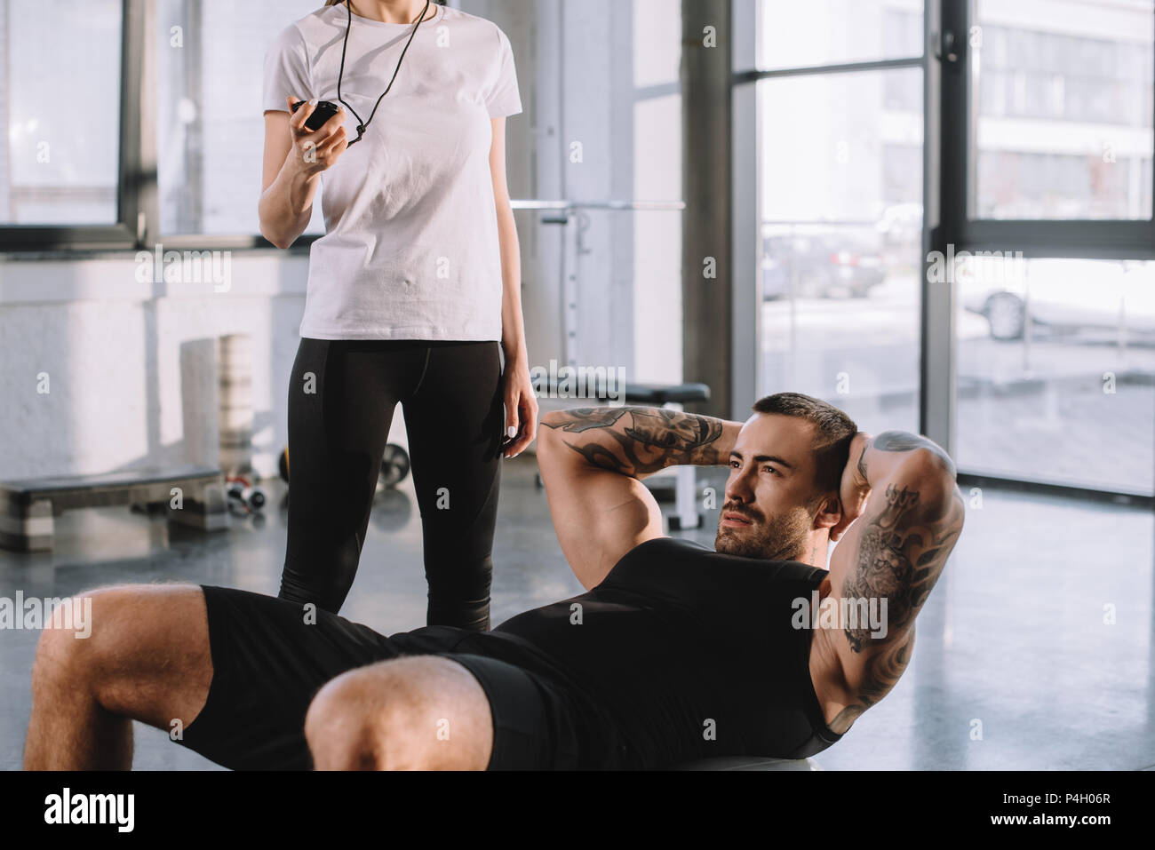 Female Personal Trainer Using Timer While Sportsman Doing Abs At Gym Stock Photo Alamy