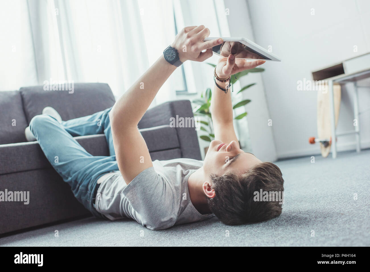 handsome teen boy using digital tablet while lying on floor Stock Photo ...