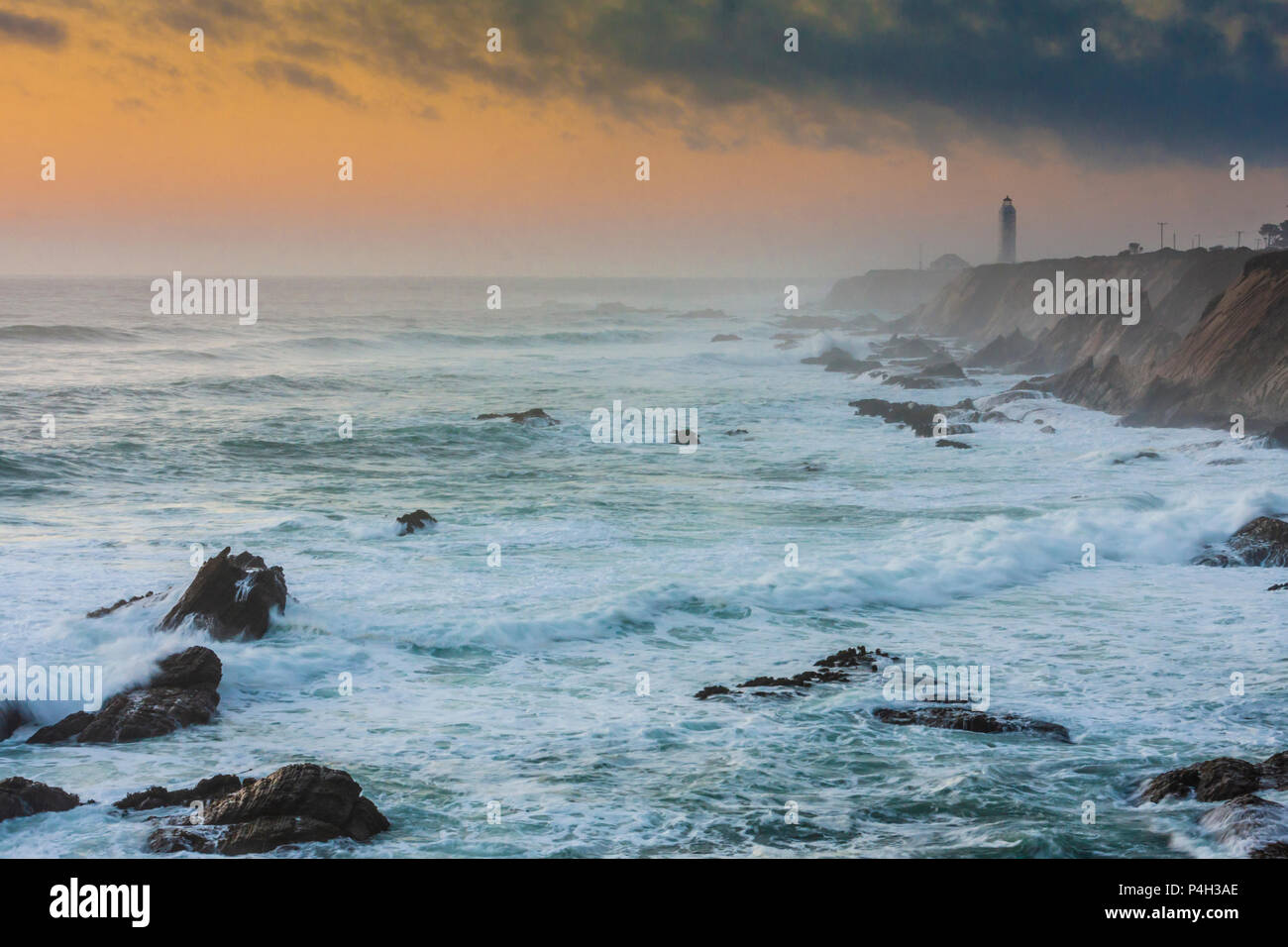 Sunset at Point Arena Lighthouse, which is cloaked in mist created by crashing waves, salt spray