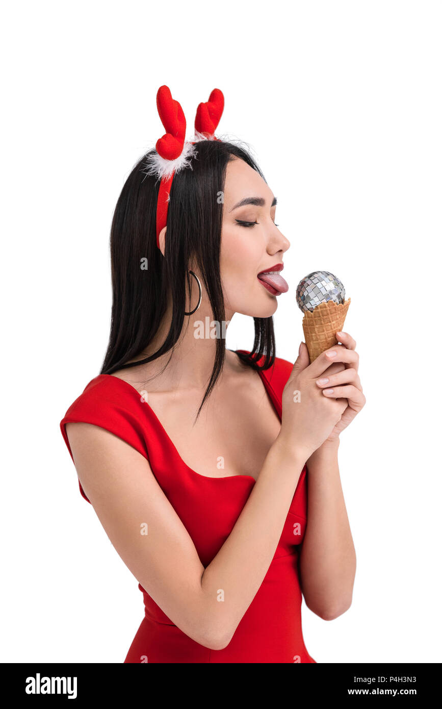 Pretty Asian Woman In Deer Costume Licking Ice Cream Cone With Christmas Ball Isolated On White