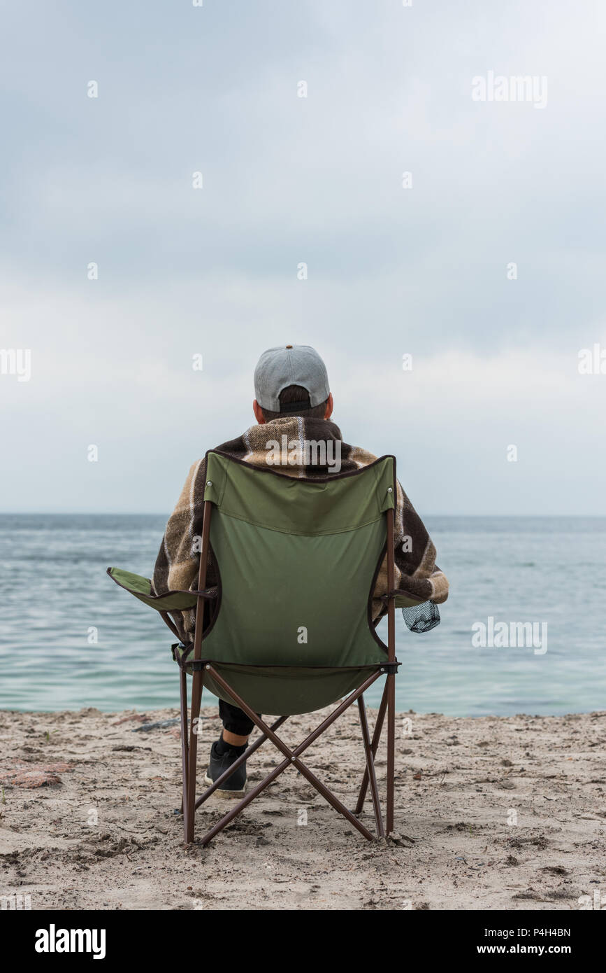 Lonely Man Sitting On Chair At Seashore On Cloudy Autumn Day Stock