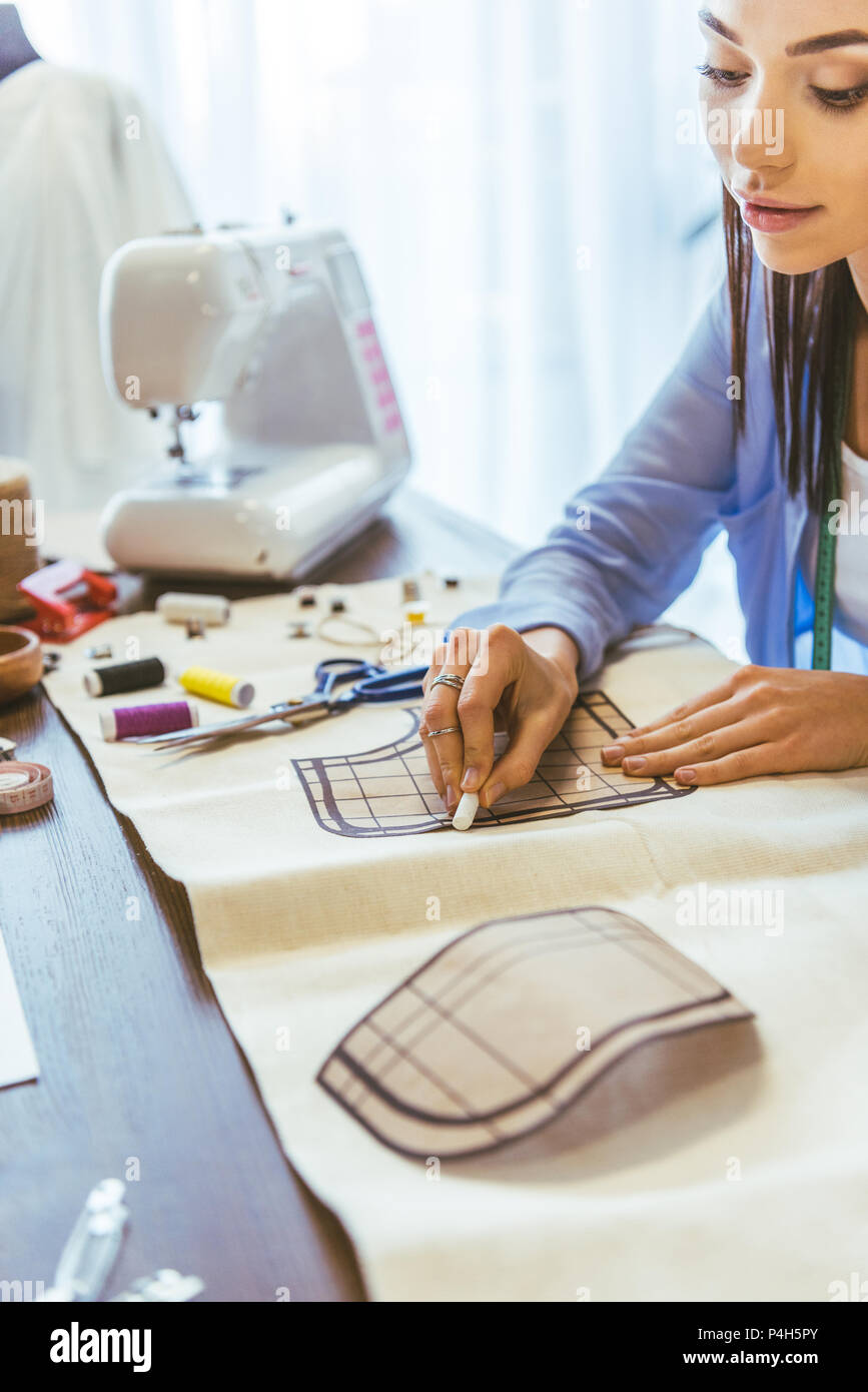 attractive seamstress marking pattern with piece of chalk Stock Photo