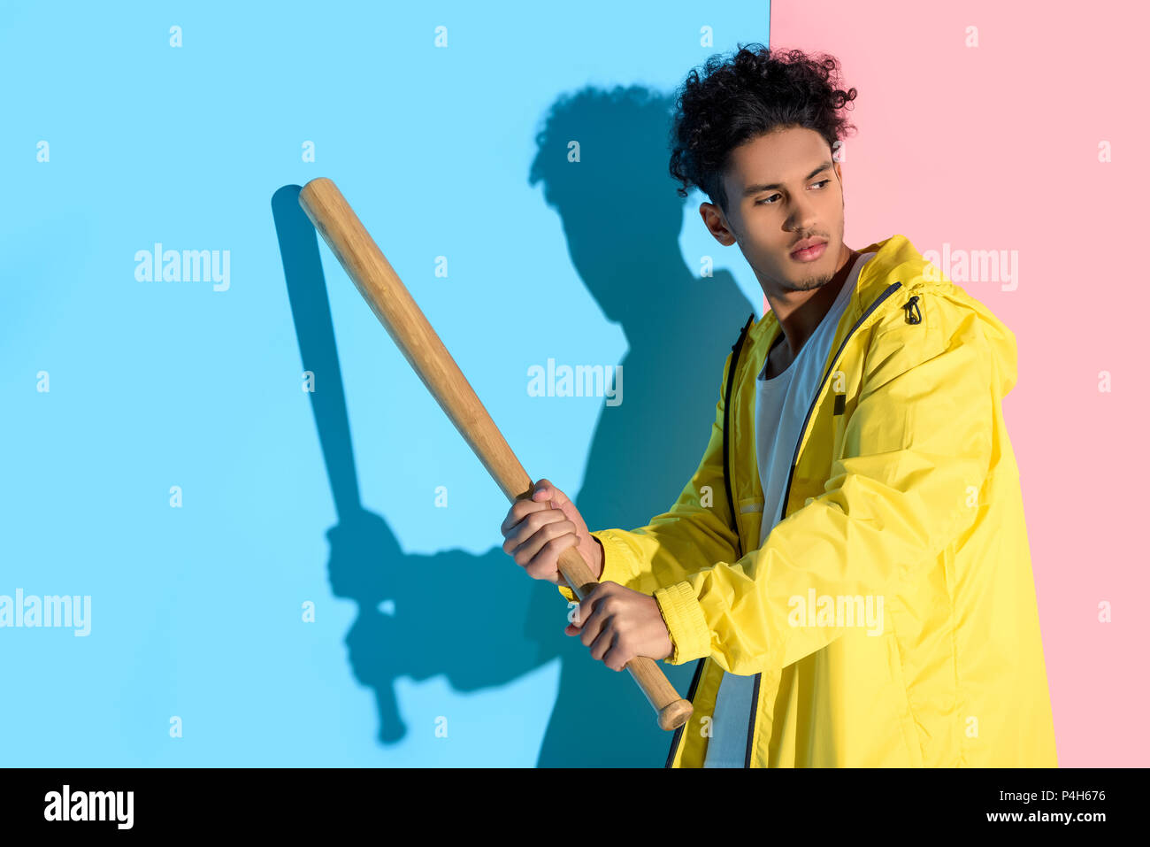 Handsome young man holding baseball bat in hands about to kick and
