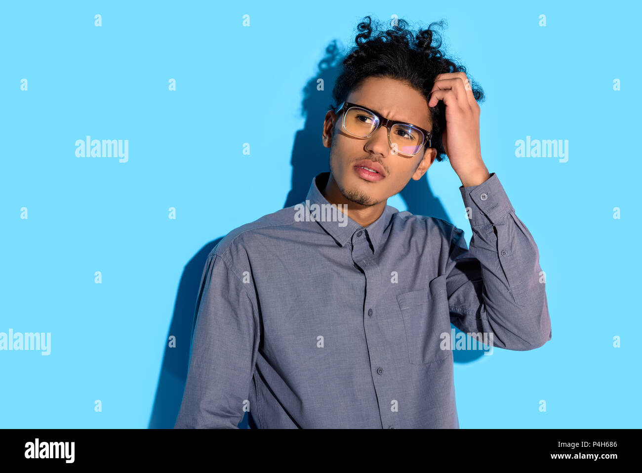 Young african amercian thoughtful man on blue background Stock Photo