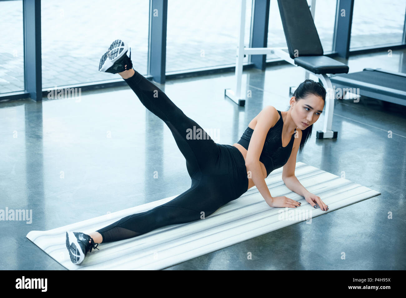 young sporty woman lifting leg on yoga mat at gym Stock Photo