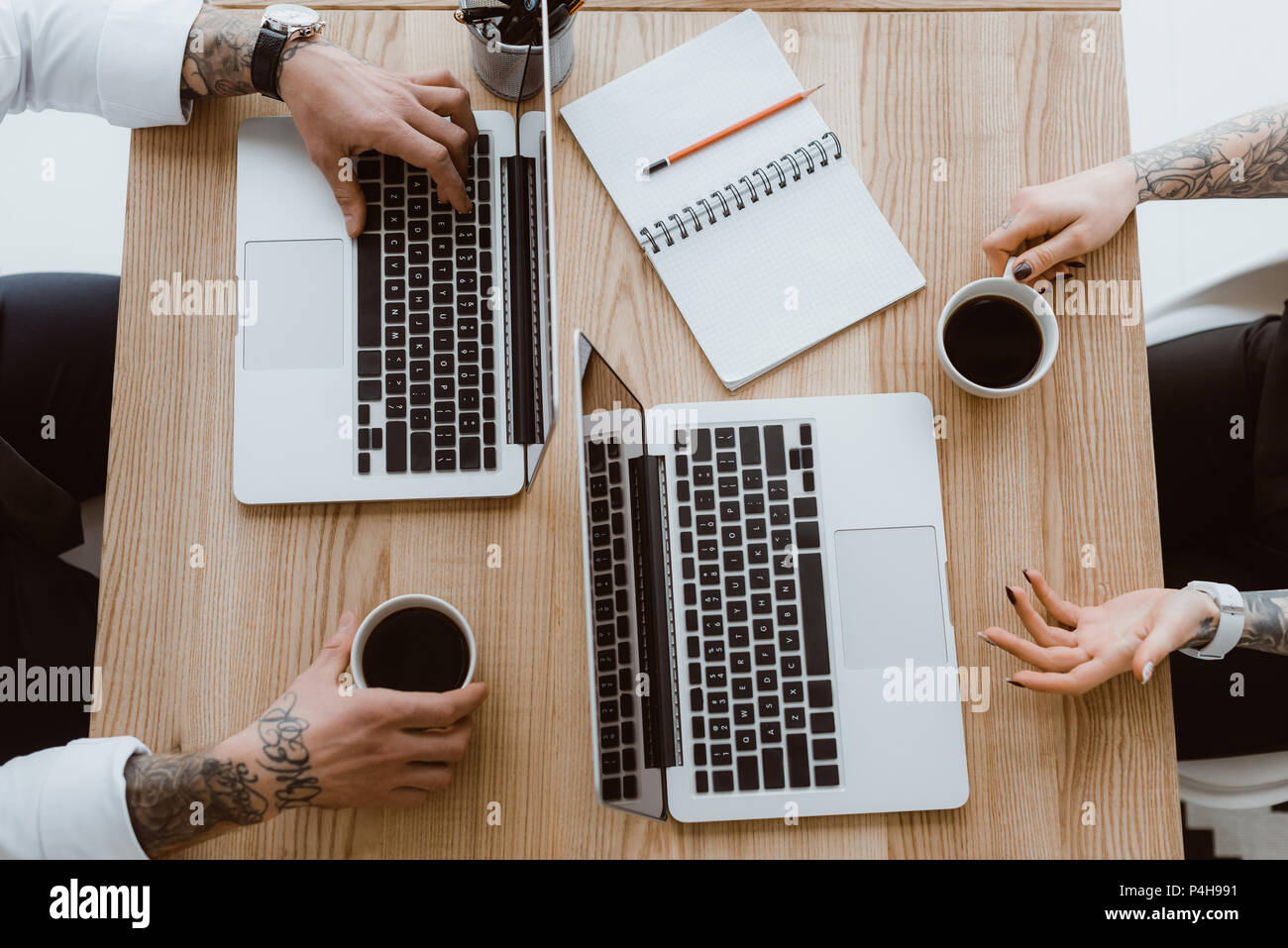 top view of colleagues using laptops and drinking coffee Stock Photo