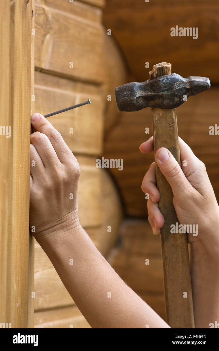 clouseup of hands hammering nail in wooden plank Stock Photo