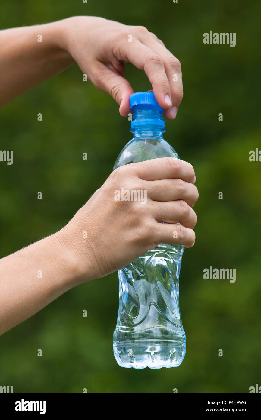 hands opening bottle with fresh water on nature background Stock Photo