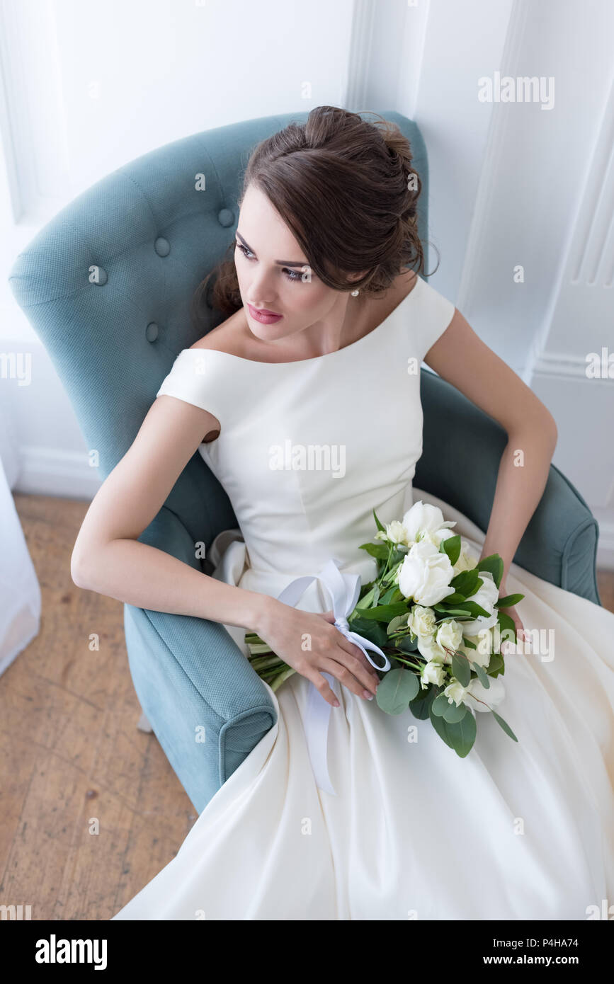 attractive bride with wedding bouquet sitting in armchair Stock Photo ...