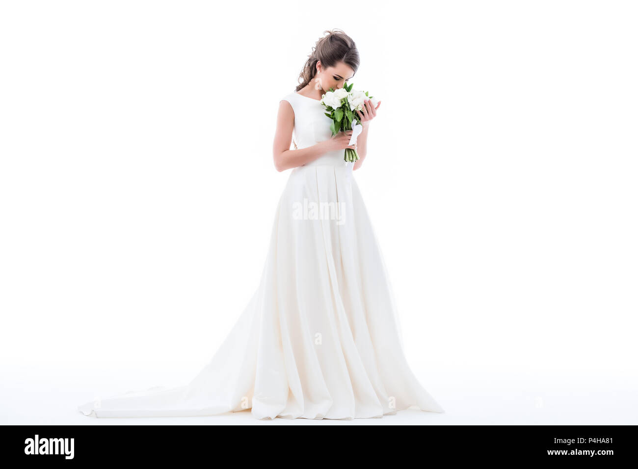 elegant bride posing in traditional dress and sniffing wedding bouquet ...