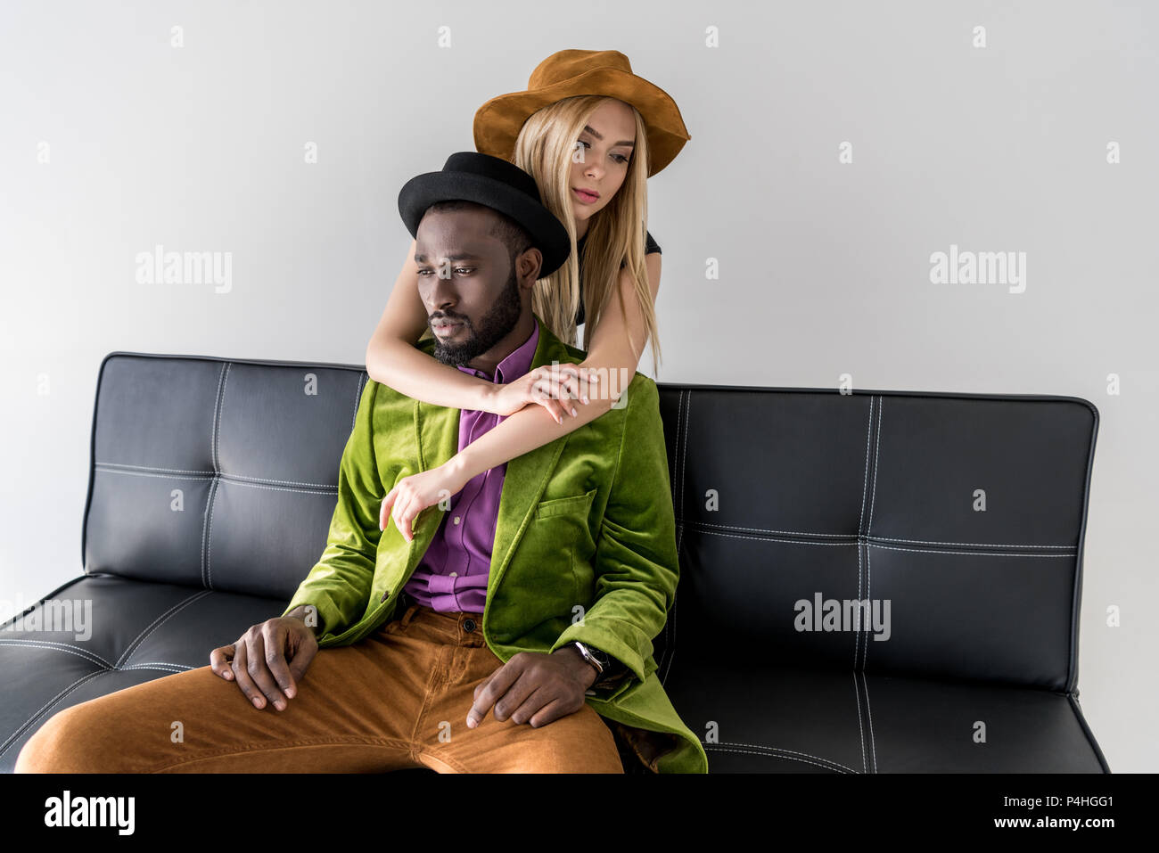 caucasian woman hugging stylish african american boyfriend on sofa ...