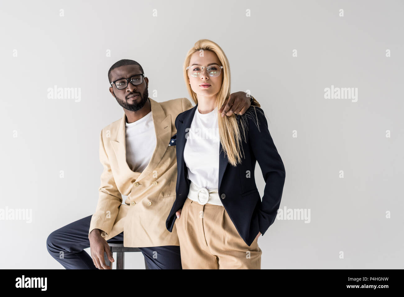 portrait of stylish young multiethnic couple in eyeglasses looking at ...