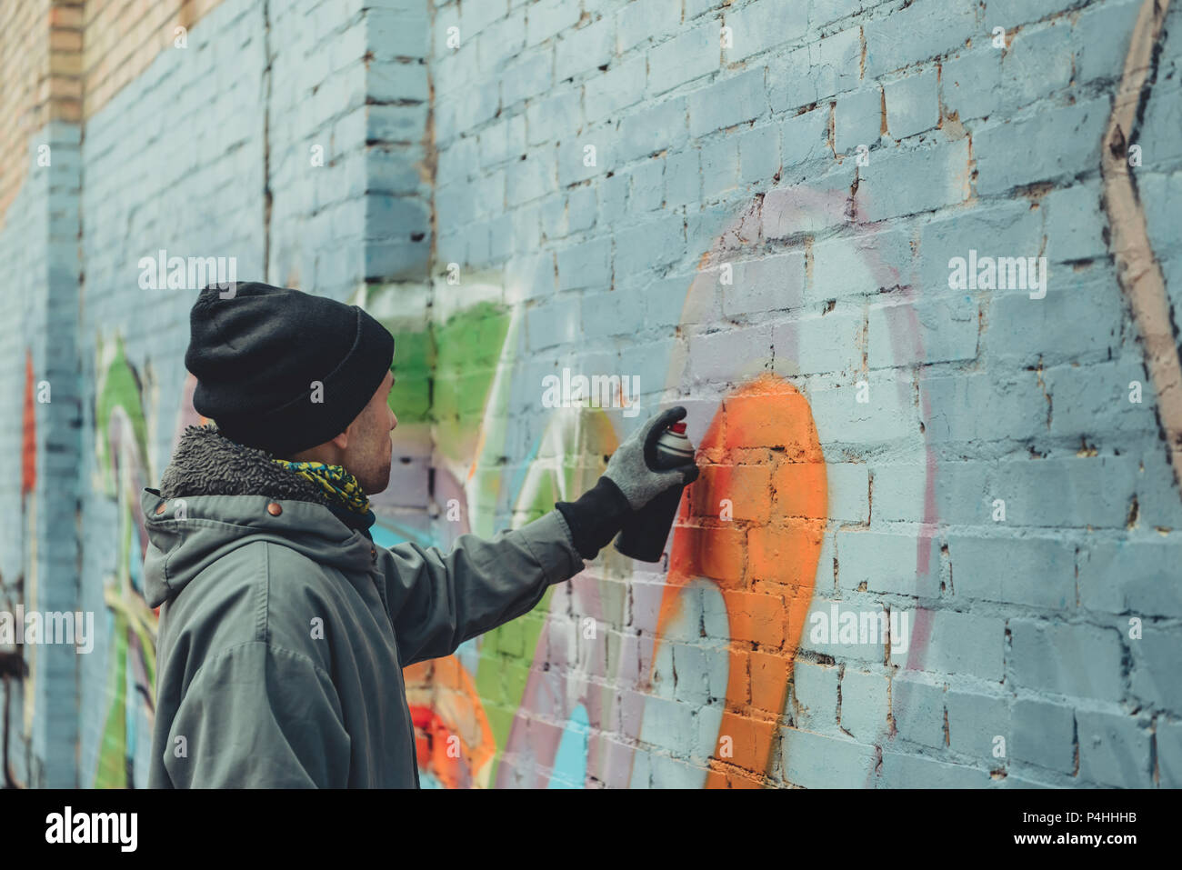 male street artist painting colorful graffiti on wall Stock Photo - Alamy
