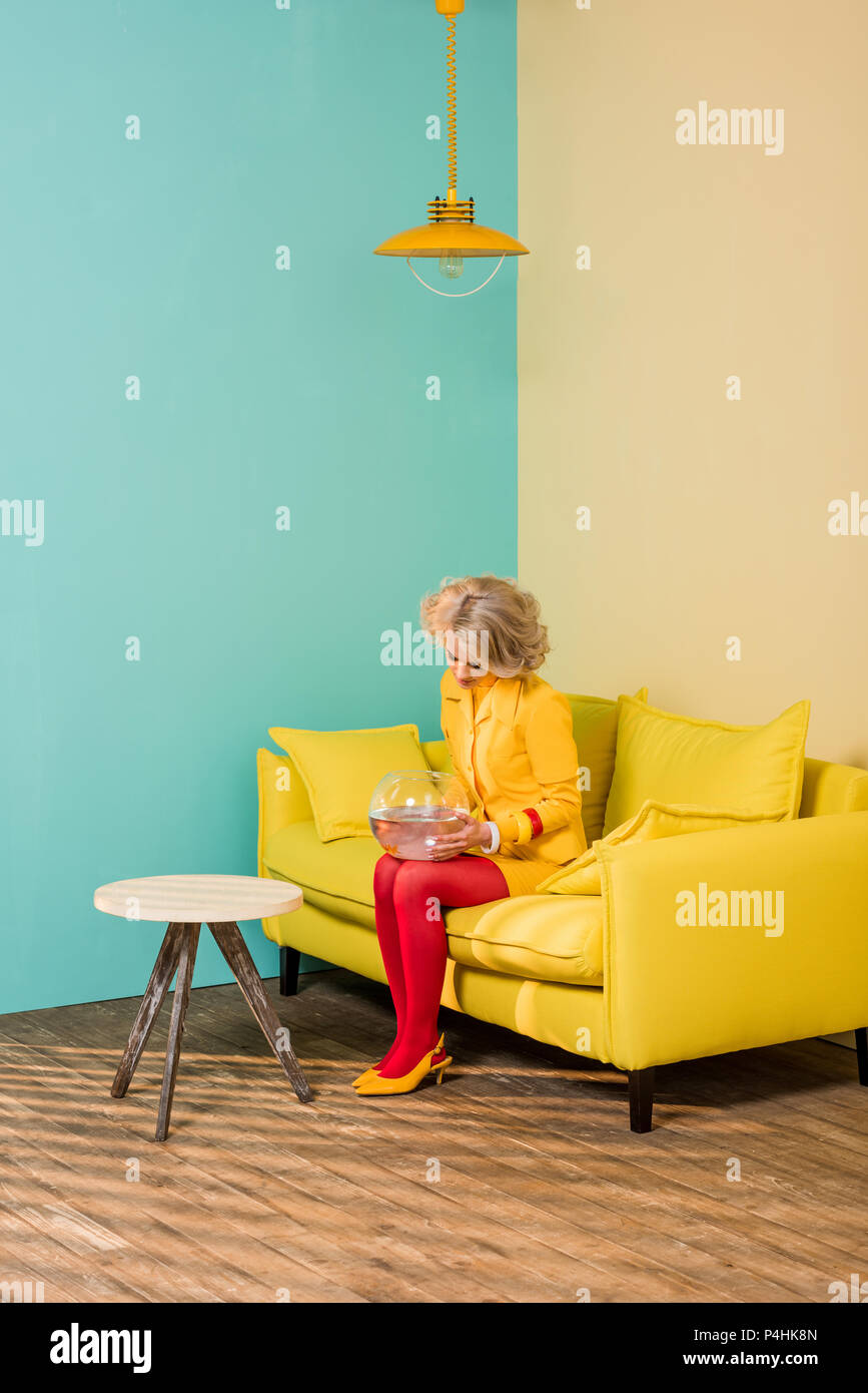 Woman In Bright Retro Clothing With Golden Fish In Aquarium Woman In Bright Retro Clothing With Golden Fish In Aquarium
