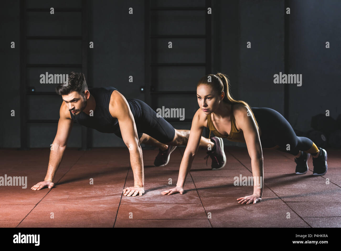 Sportswoman and sportsman doing push ups in gym in sports hall Stock ...