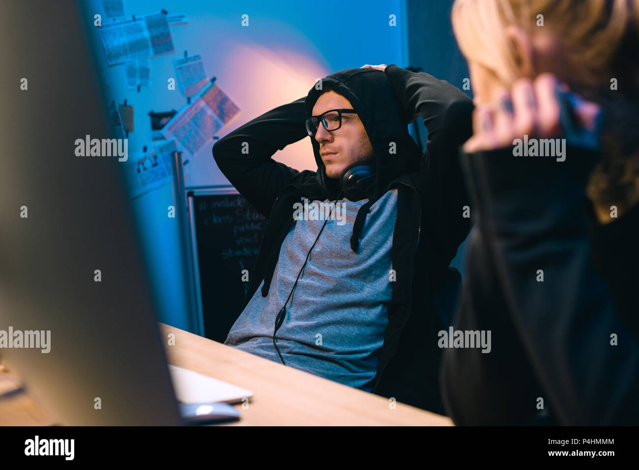 female hacker looking at depressed accomplice at workplace Stock Photo