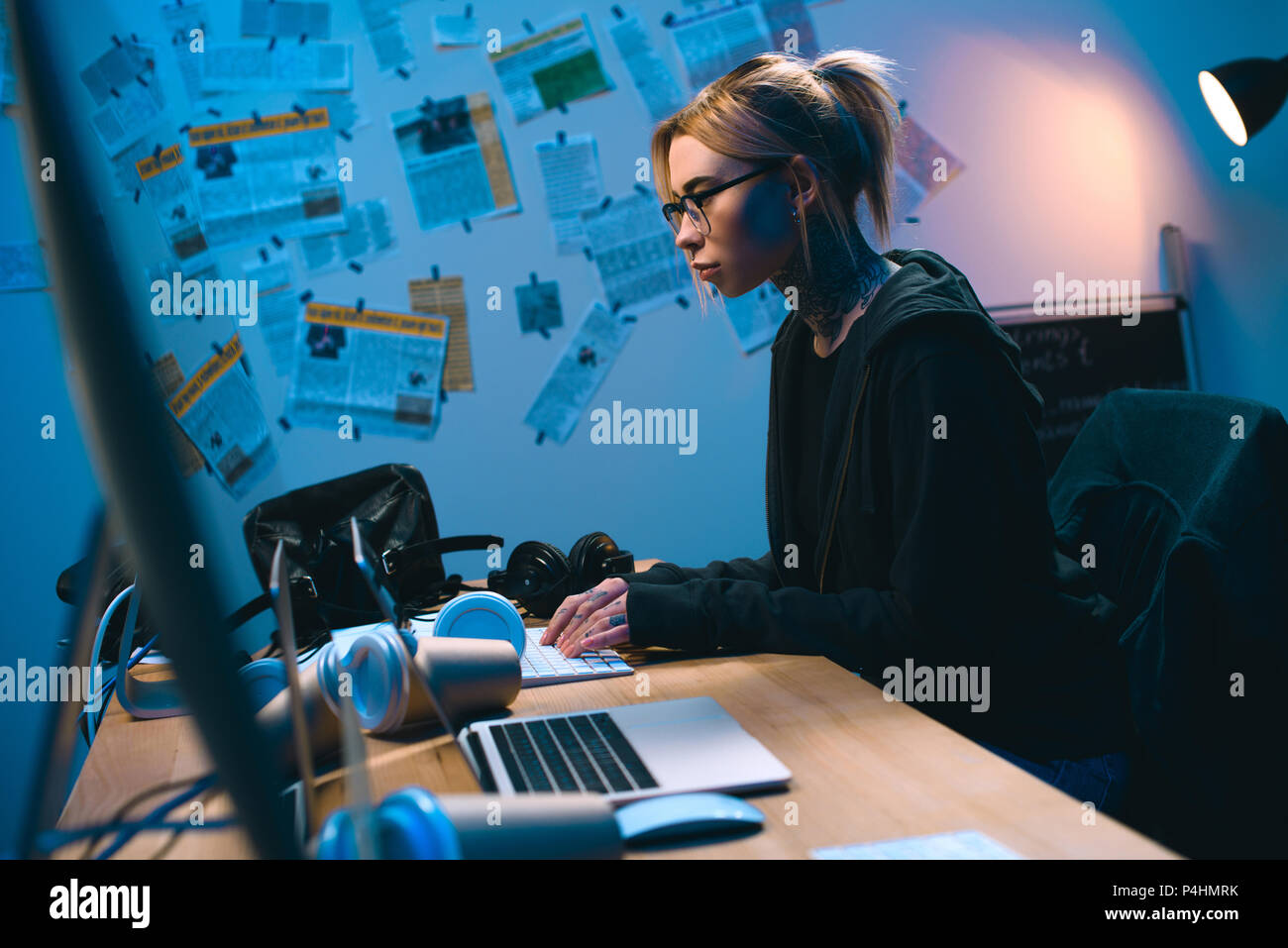 side view of young female hacker developing malware in dark room Stock Photo