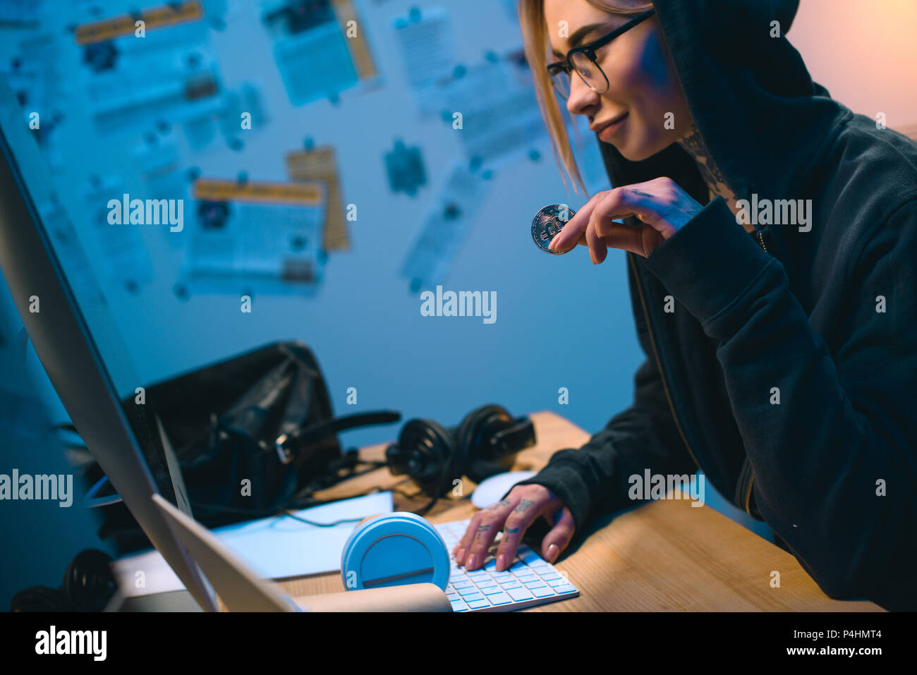side view of young female hacker holding bitcoin Stock Photo
