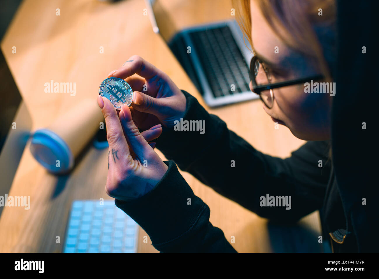 close-up shot of young female hacker holding bitcoin Stock Photo