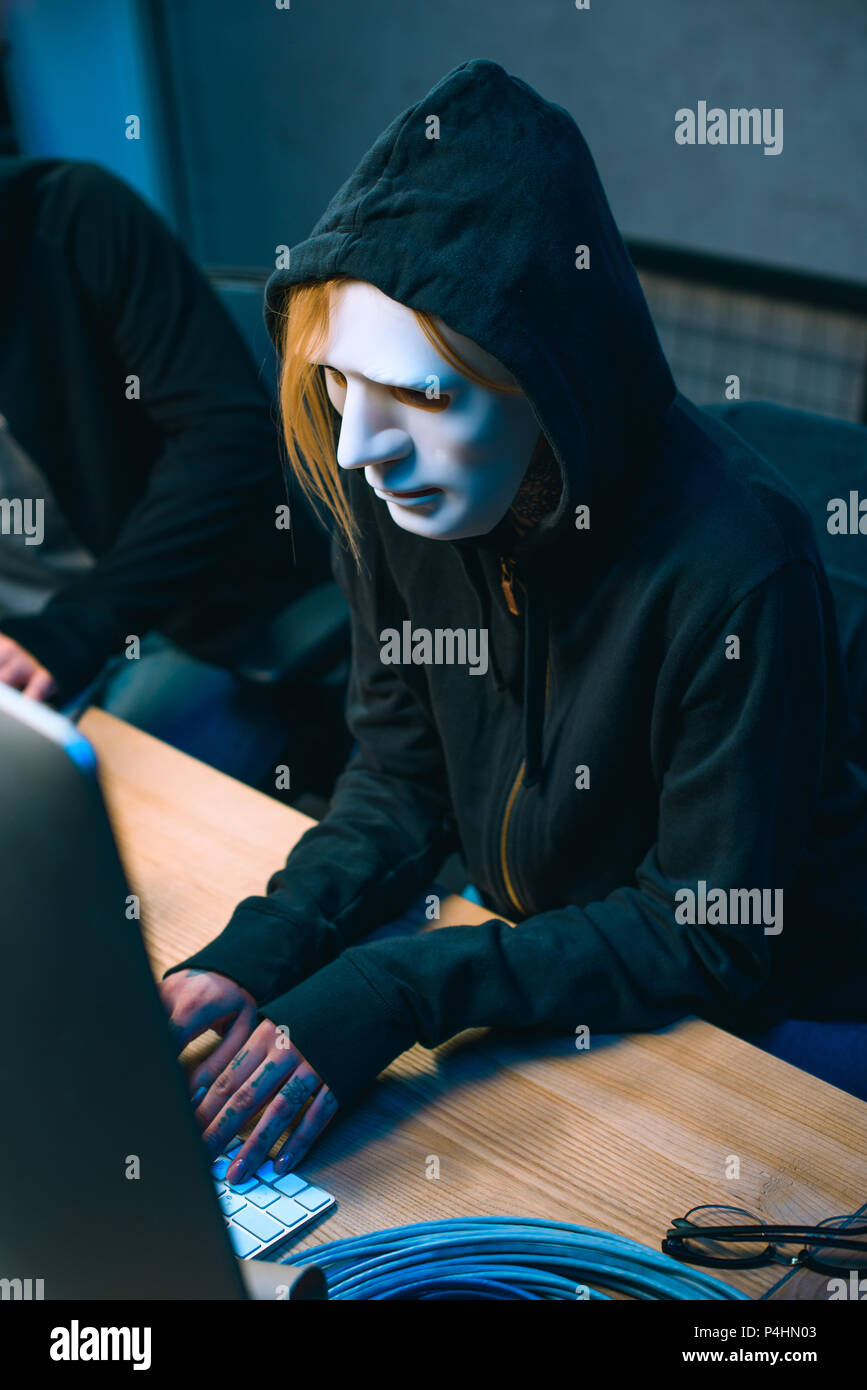 high angle view of hacker in mask working with computer to develop malware Stock Photo