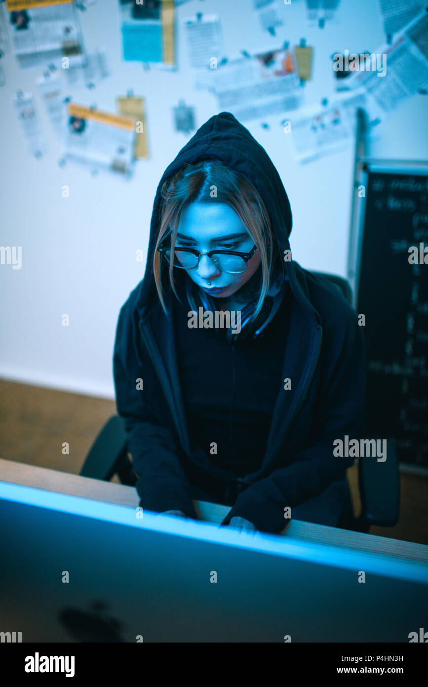 high angle view of young female hacker developing malware under blue light Stock Photo