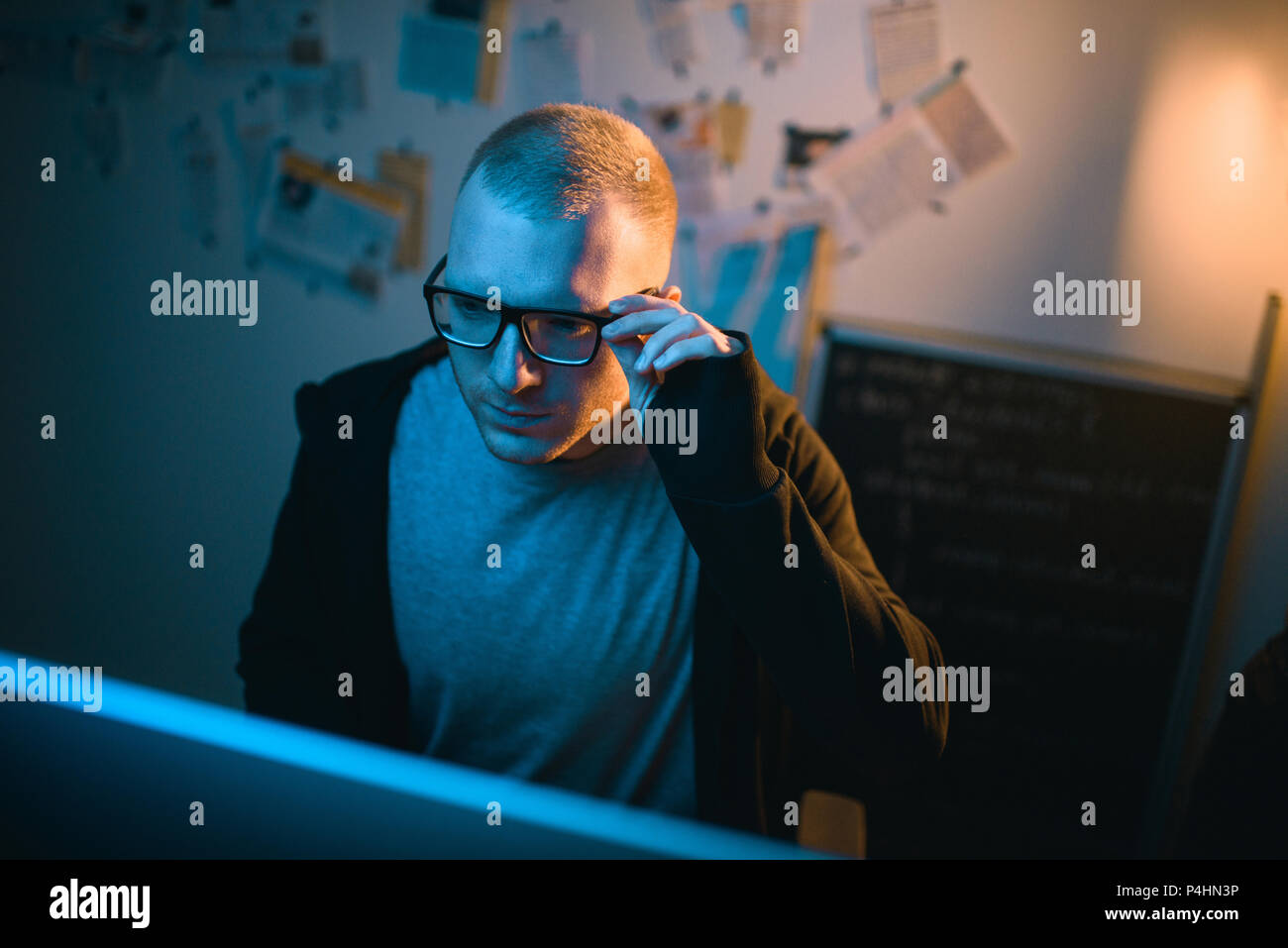 high angle view of young hacker developing malware in dark room Stock Photo