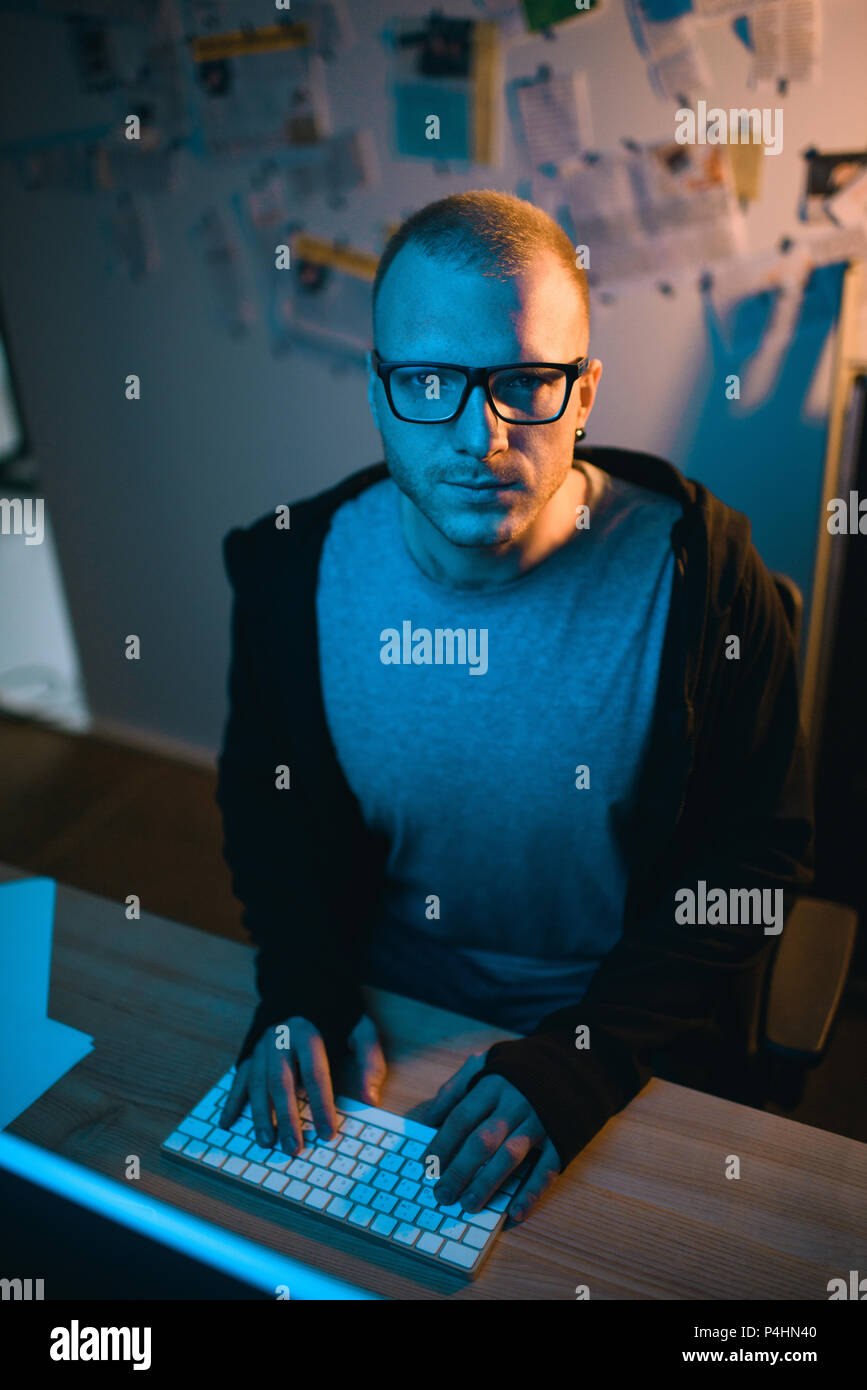 high angle view of hacker sitting at workplace and looking at camera Stock Photo