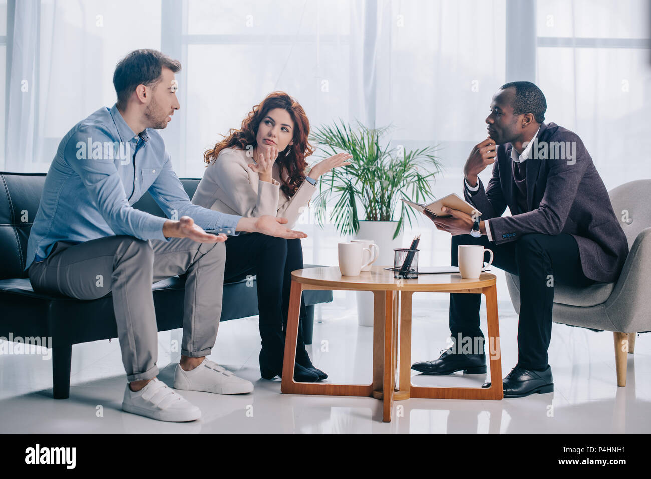 Quarreling couple talking to african american psychiatrist in office
