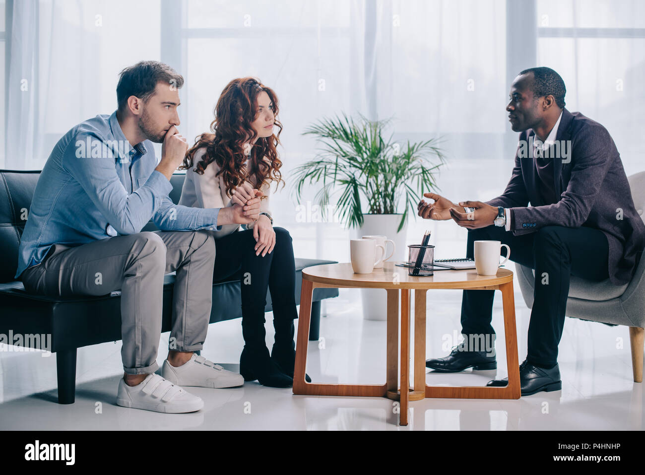 Smiling african american psychiatrist talking to young couple in office
