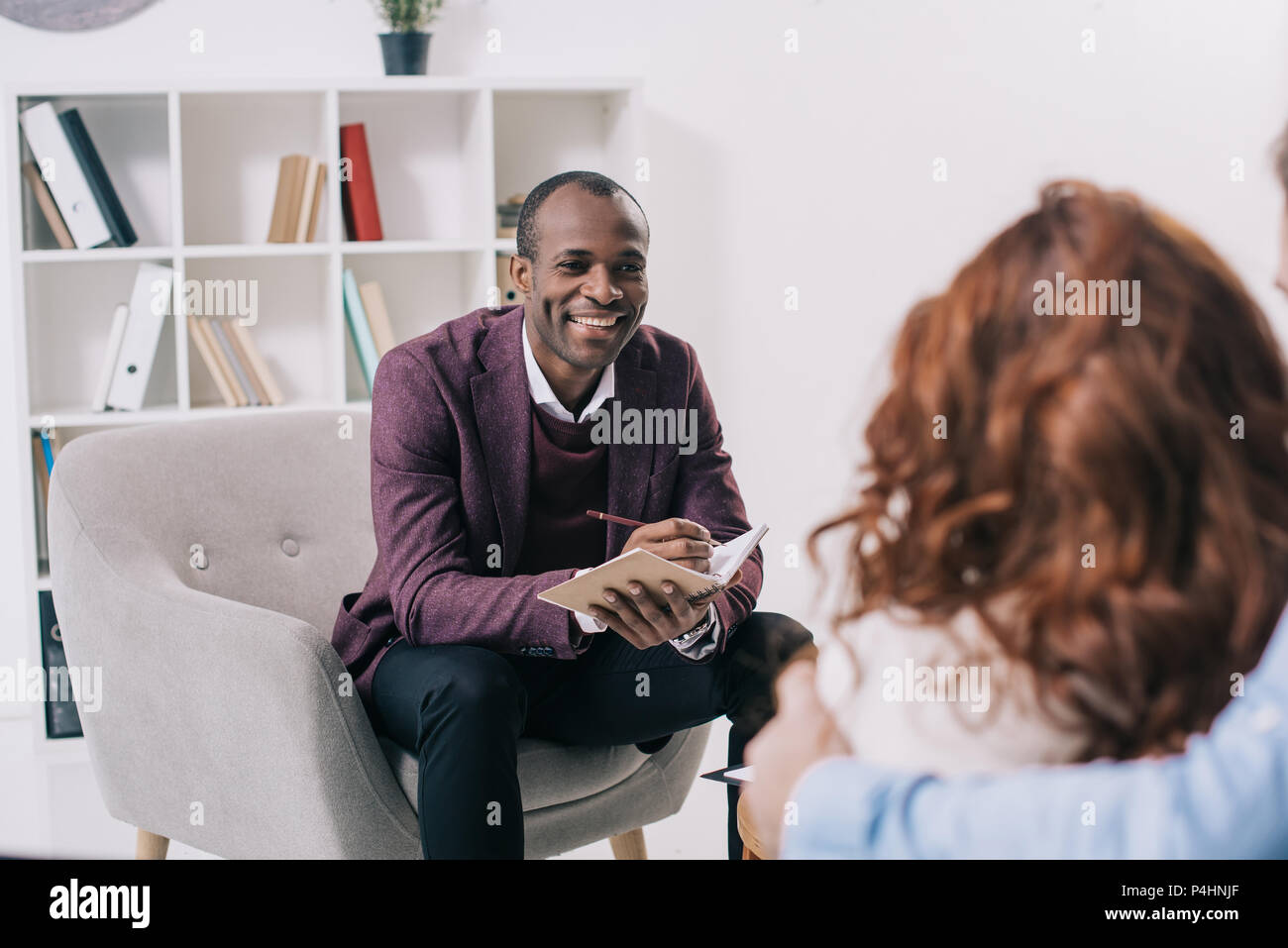 Smiling african american psychiatrist talking to young couple Stock