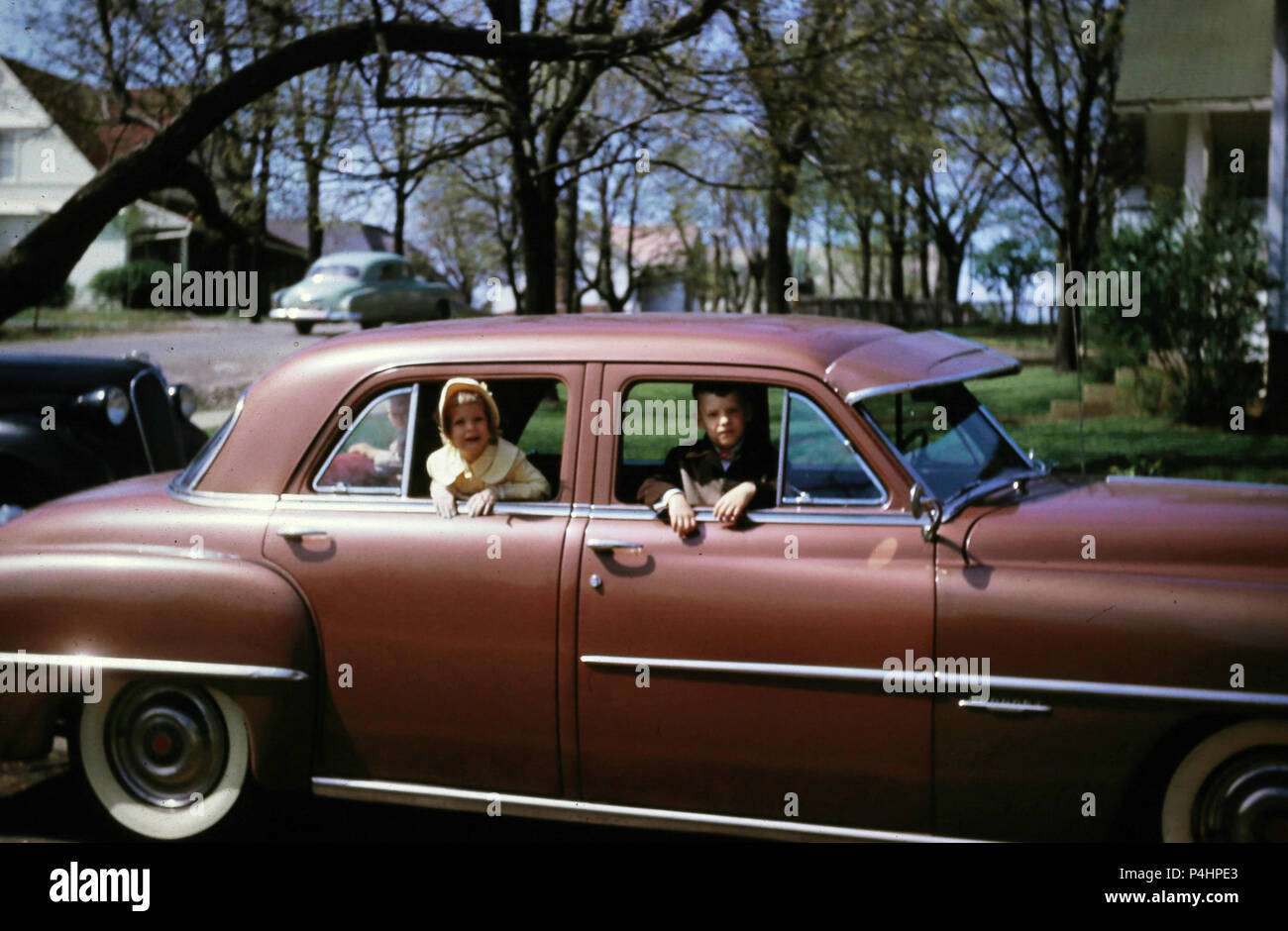 1950s, children looking out of the window from a automobile in a home driveway, USA Stock Photo