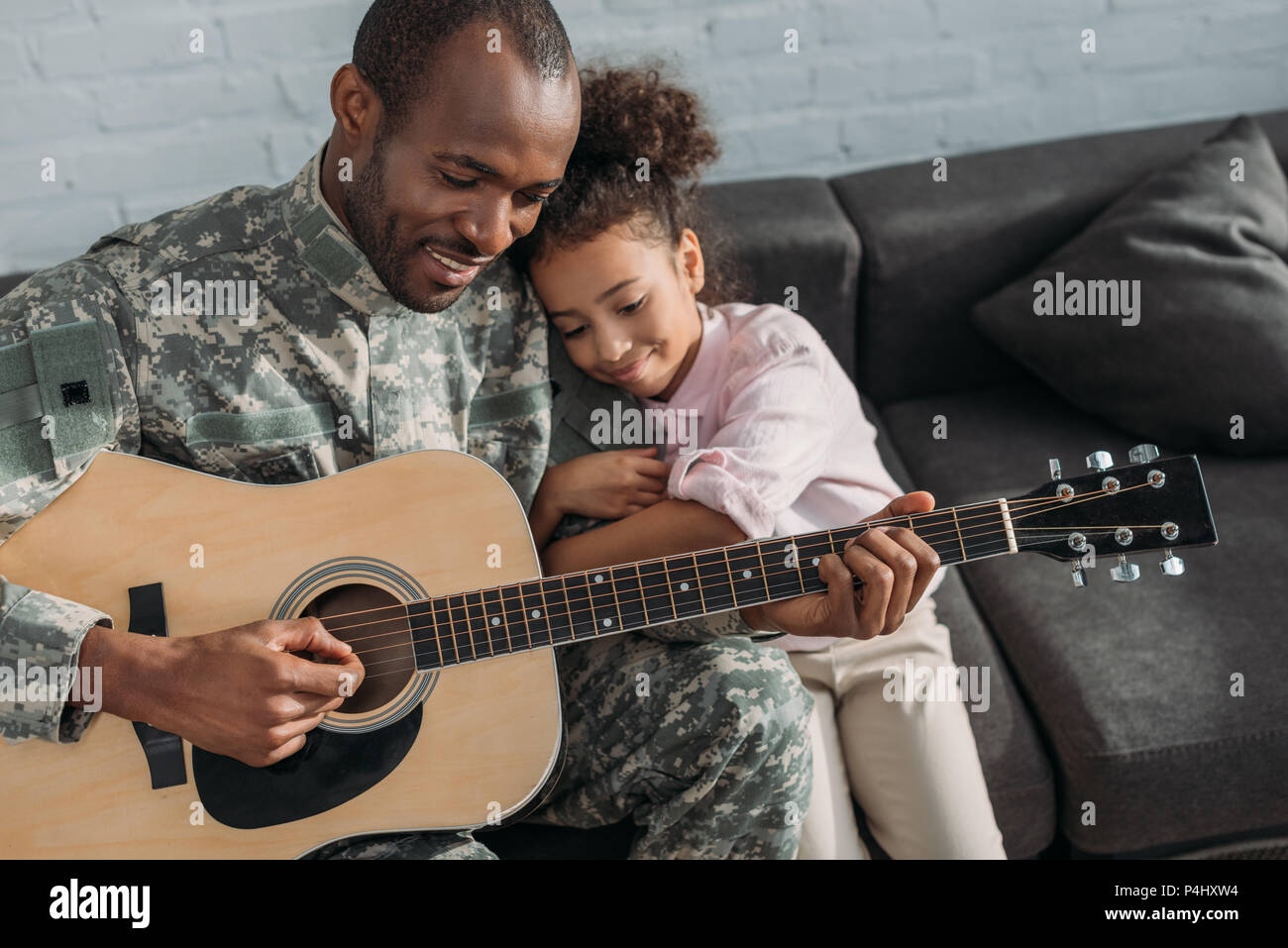 Smiling soldier playing guitar and hugging daughter Stock Photo Alamy