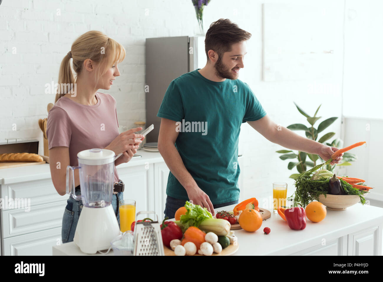 couple of vegans using tablet with recipe for preparing food at kitchen Stock Photo