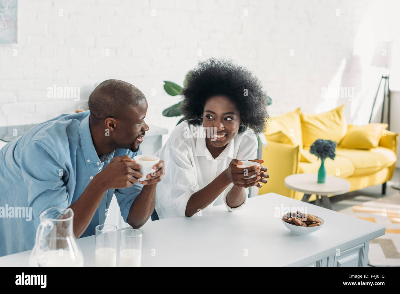 smiling african american couple with cups of coffee in morning together ...