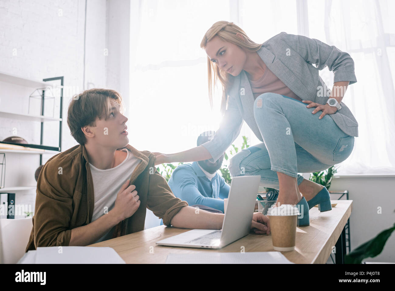 young businesswoman threatening and grabbing collar of colleague in