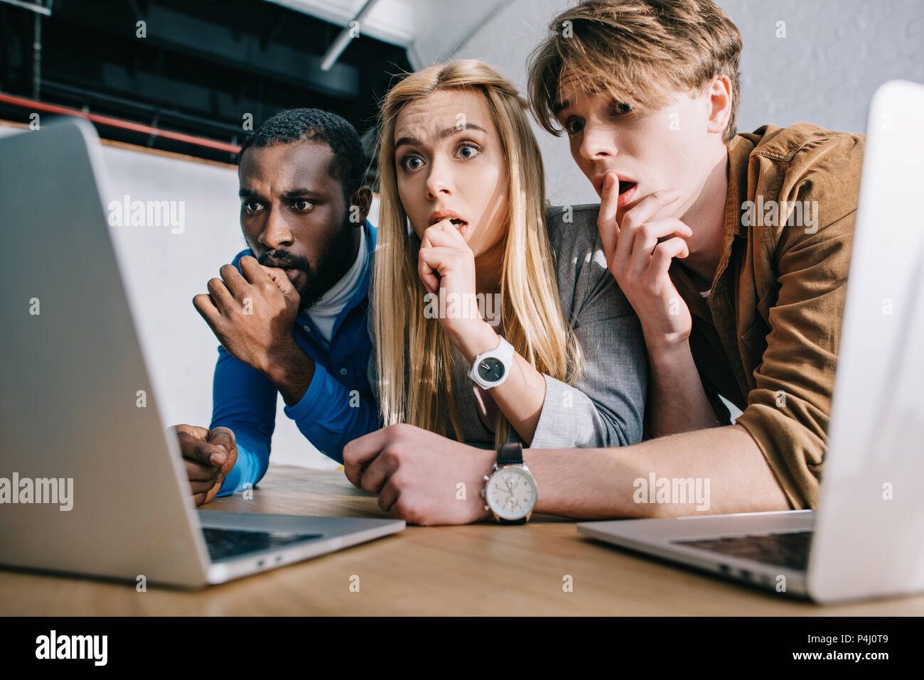 scared multicultural business colleagues watching on laptop screen Stock Photo