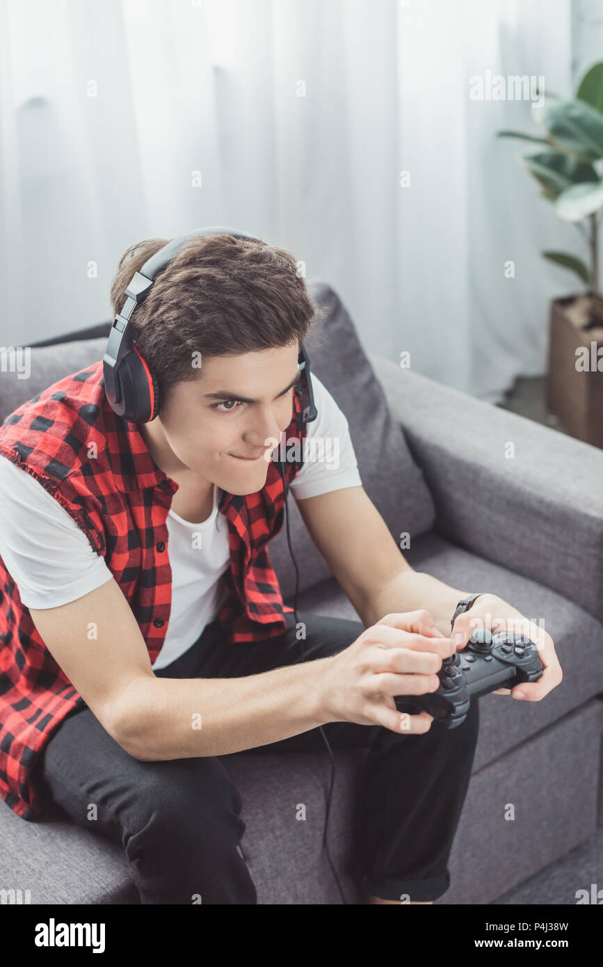 teen boy with headset playing video game with joystick at home Stock