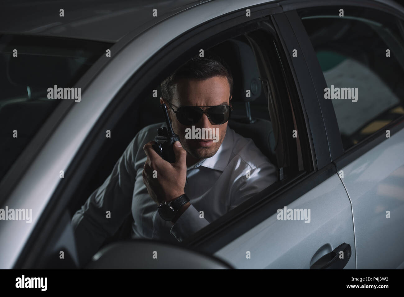 undercover male agent in sunglasses doing surveillance and using talkie  walkie in car Stock Photo - Alamy