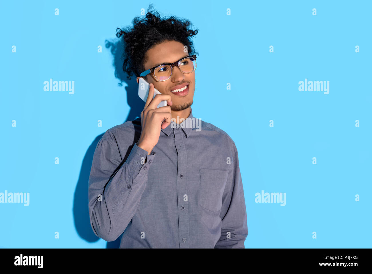 Young african amercian businessman talking on phone on blue background Stock Photo