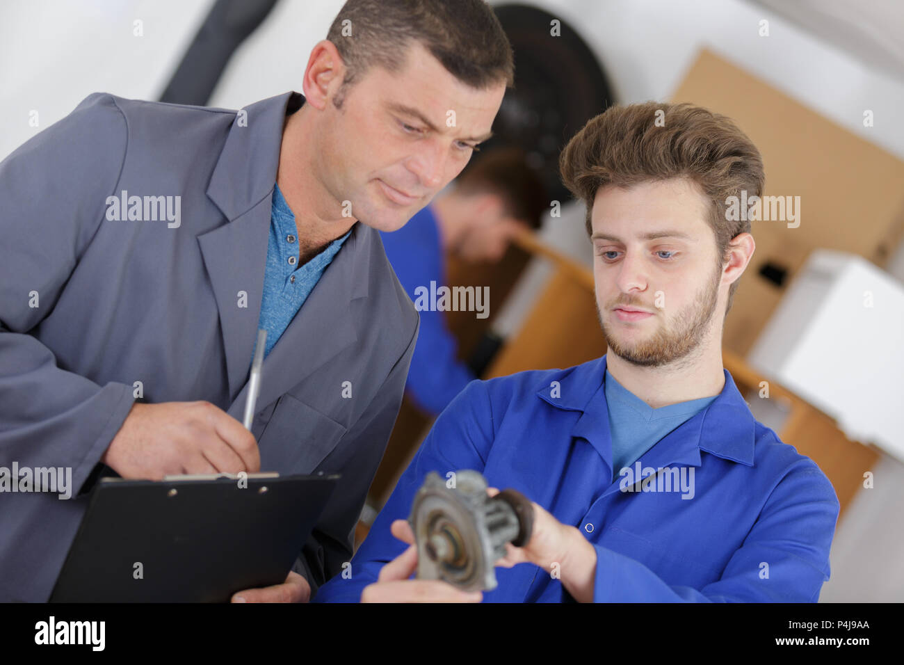 Trainee mechanic identifying part Stock Photo Alamy