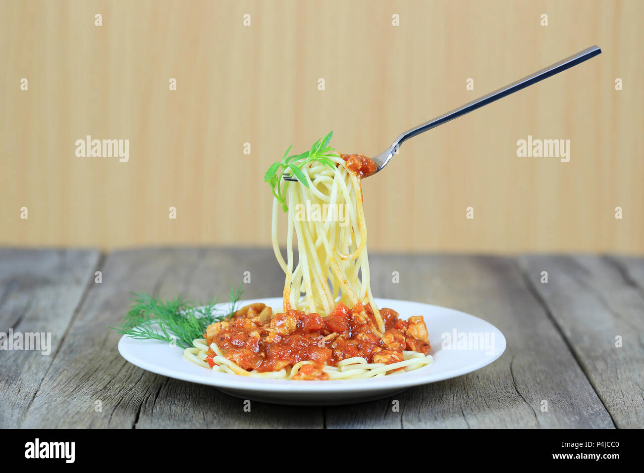 Spaghetti with tomato sauce on silver fork of floating in the white dish on wooden floor,concept of eating good food is health care. Stock Photo
