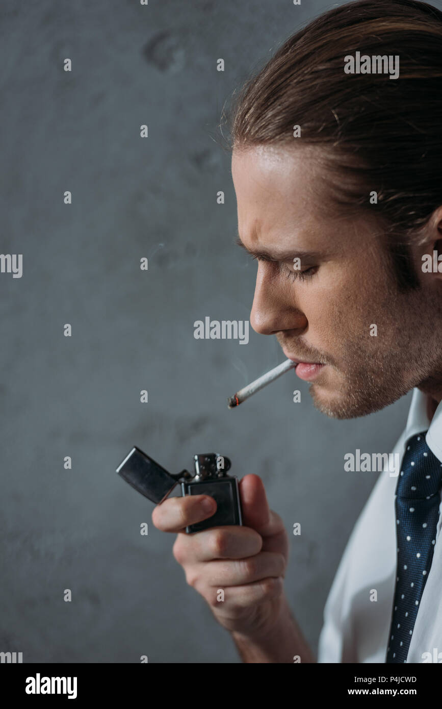 closeup portrait of man smoking cigarette in front of concrete wall