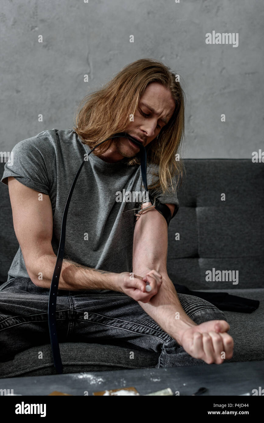 young addicted junkie doing heroin injection Stock Photo