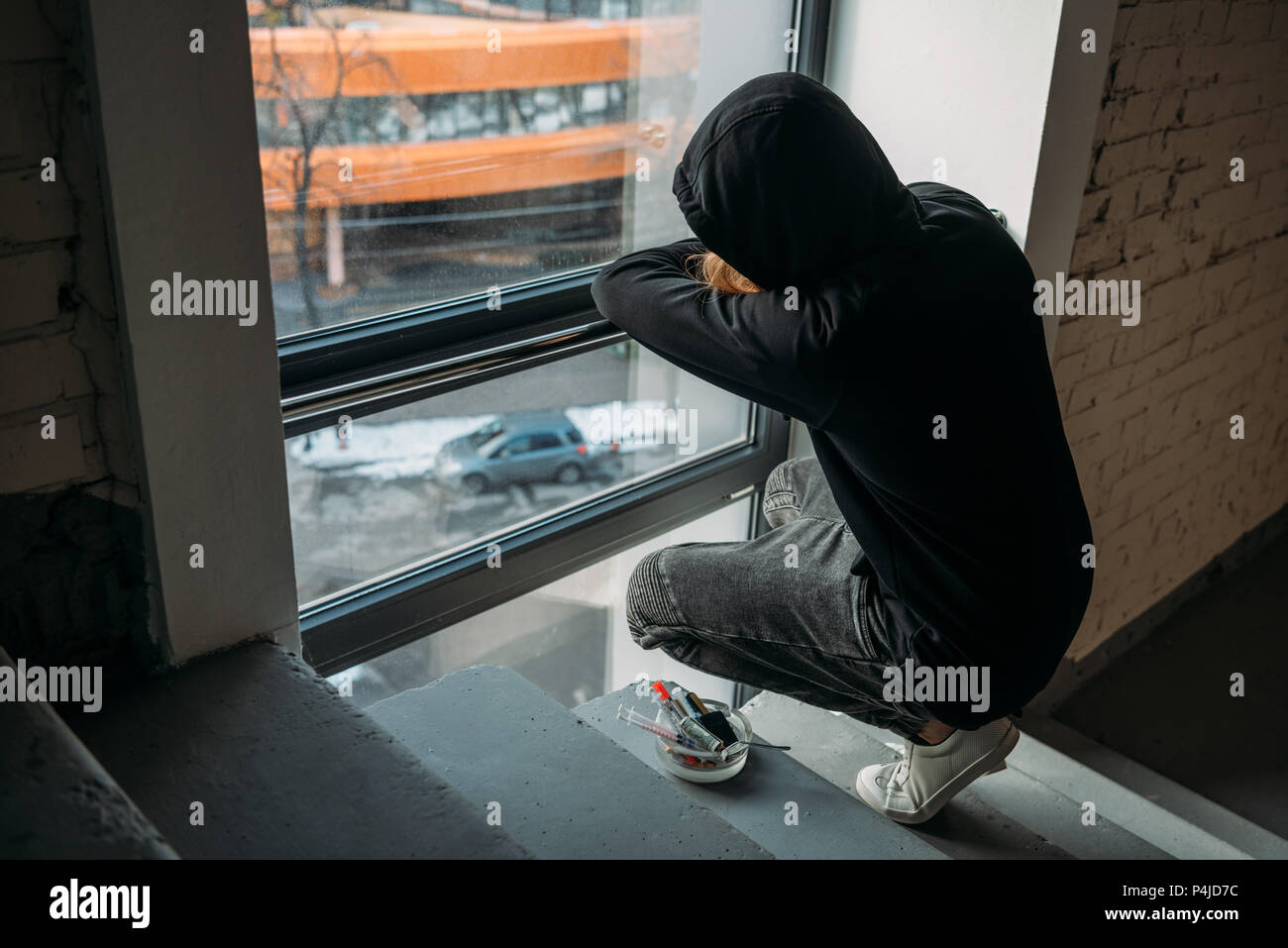 addicted man sitting on stairs and looking at window Stock Photo