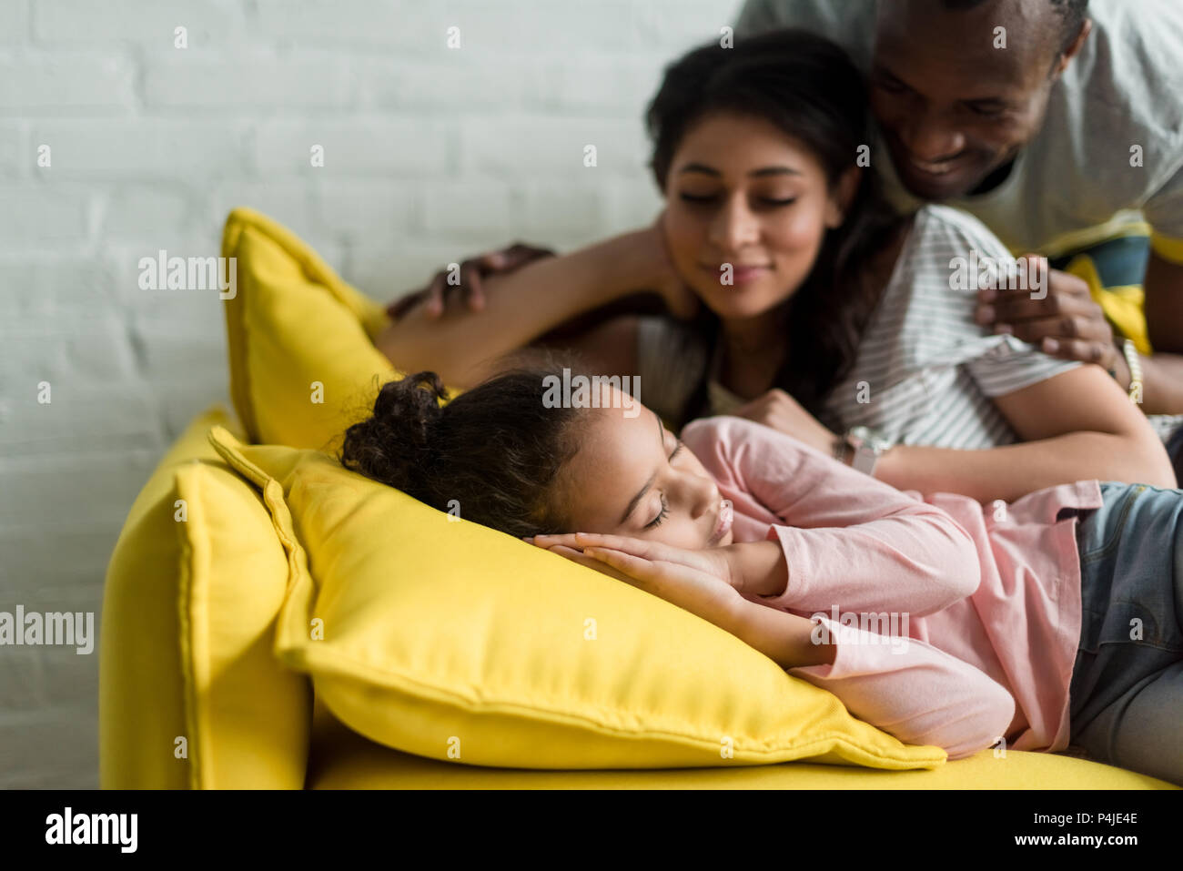 happy parents watching on their daughter sleeping on couch Stock Photo